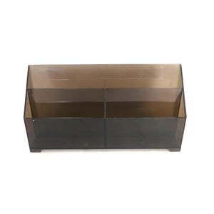 May include: A clear, brown plastic desk organizer with two compartments. The organizer has a rectangular shape and is made of translucent plastic.