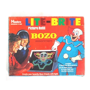 May include: A vintage Lite-Brite picture refill box with the text "BOZO assortment." The box features a clown illustration and images of children. The box is red with blue, yellow, and green text.