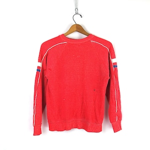 Puede incluir: Sudadera roja de manga larga con ribetes blancos y azules en las mangas. La sudadera tiene cuello redondo y dobladillo de canalé.