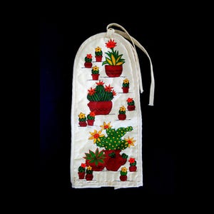 Puede incluir: Porta-toallas de cocina de tela blanca con un diseño de cactus colorido. El porta-toallas presenta una variedad de cactus en macetas rojas, verdes y amarillas con flores amarillas.