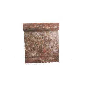 May include: A small, rectangular metal object with a rolled top edge and a serrated bottom edge. The object has a rusty, weathered appearance, with shades of brown and orange. The item is isolated on a white background.