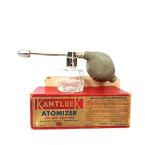 May include: Vintage KANTLEEK Atomizer with glass liquid-tube. The red box has the product name and instructions. The atomizer has a clear glass bottle, a silver metal nozzle, and a gray rubber bulb.