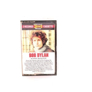 May include: A cassette tape of Bob Dylan's album "Blonde on Blonde." The cover features a portrait of Dylan with the album title in red. The cassette case is clear, and the label reads "2 Records 2 on 1 Cassette."