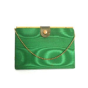 May include: A green satin evening bag with a gold chain strap and a gold button closure.