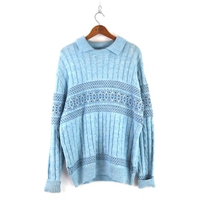 Puede incluir: Un suéter de punto de cable azul claro con un patrón de copo de nieve azul oscuro alrededor del medio.