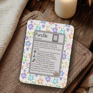 Puede incluir: Una funda para lector de libros electrónicos Kindle con un colorido estampado de criaturas de dibujos animados y estrellas. La funda presenta el texto "Kindle Artifact" y una descripción de sus características. La funda está sobre una superficie texturizada.