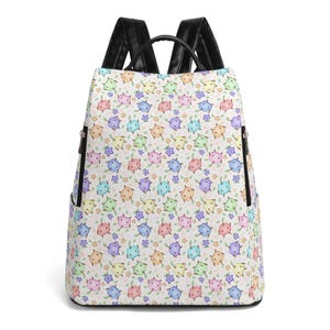 Puede incluir: Una mochila blanca con un colorido estampado de criaturas de dibujos animados, estrellas y hojas. La mochila tiene correas negras y un asa negra. Cuenta con dos bolsillos laterales y un cierre de cremallera.