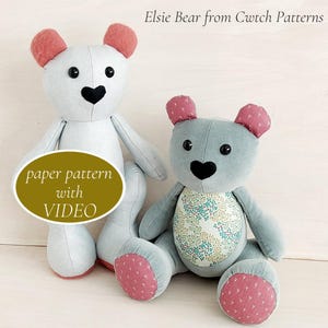May include: Two fabric teddy bears labelled Elsie Bear from Cwtch Patterns. One is light blue with pink ears and a black heart nose. The other is grey with pink ears, a black heart nose, and a floral belly patch. Includes a paper pattern with VIDEO.