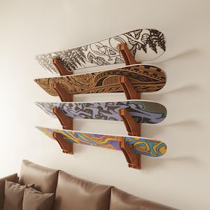 Puede incluir: Cuatro tablas de snowboard coloridas están montadas en una pared con soportes de madera. Las tablas de snowboard tienen diferentes diseños y patrones.