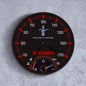 May include: A black round wall clock with a speedometer design. The clock face features red and white markings, a Mustang logo, and the word "MUSTANG". It includes a digital display and various gauges.