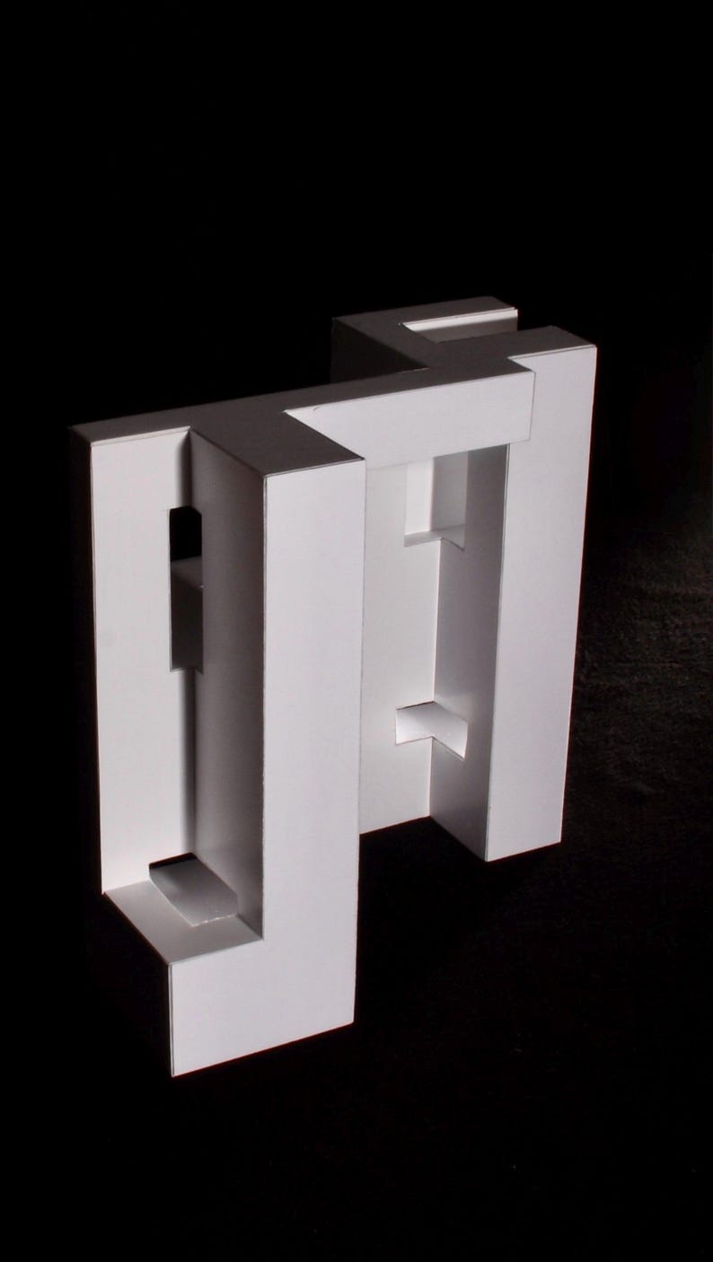 K&ouml;nnte beinhalten: Eine wei&szlig;e, geometrische Papierskulptur mit minimalistischem Design. Die Skulptur weist rechteckige und quadratische Ausschnitte auf, die einen dreidimensionalen Effekt erzeugen. Das Kunstwerk ist vor einem schwarzen Hintergrund platziert.