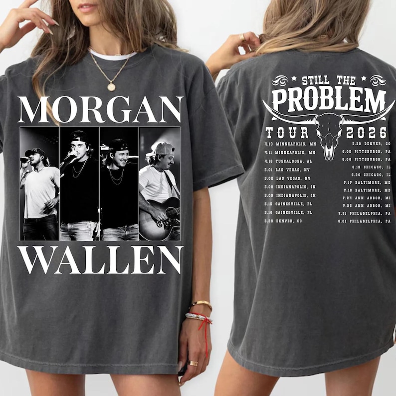 May include: Dark gray t-shirt featuring the text "MORGAN WALLEN" in white block letters above a black and white photo collage of the artist. The back of the shirt displays "STILL THE PROBLEM TOUR 2026" with a bull skull graphic and tour dates.