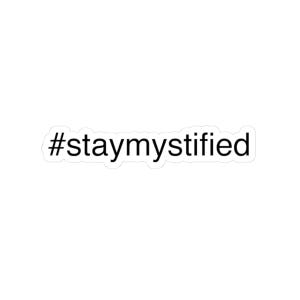 Könnte beinhalten: Ein weißer Aufkleber mit dem schwarzen Text "#staymystified". Der Hashtag und die Phrase sind in einer serifenlosen Schriftart. Der Aufkleber hat einen weißen Rand.