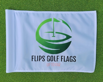 Può includere: Bandiera da golf bianca con un logo verde raffigurante un campo da golf e la scritta "FLIPS GOLF FLAGS UP TO PAR". La bandiera è rettangolare e si trova su una superficie verde.