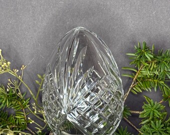 May include: A clear crystal egg-shaped vase with a cut glass design. The vase is sitting on a bed of green moss.