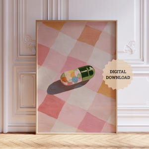 Könnte beinhalten: Gerahmter digitaler Kunstdruck mit einer großen grünen und bunten Pille auf einem rosa-orangenen karierten Hintergrund. Das Kunstwerk ist mit "DIGITALER DOWNLOAD" in Sonnenform beschriftet.