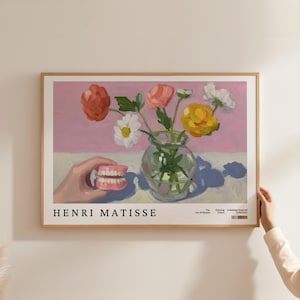 May include: A framed art print depicting a still life with a vase of flowers and a set of dentures. The flowers are in shades of red, pink, yellow, and white. The print has the text "HENRI MATISSE" at the bottom.