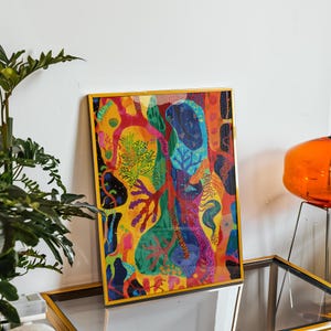 May include: A colourful framed art print with an abstract design. The artwork displays a variety of organic shapes and patterns in shades of yellow, red, blue, and green. The frame is gold, adding a touch of elegance to the piece.