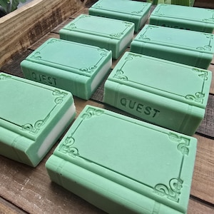 May include: A collection of rectangular light green bars shaped like books, each featuring an embossed decorative border and the word QUEST imprinted on the side. The bars have a solid light green top and a white base layer, arranged in rows.