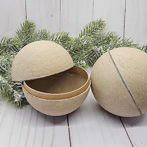 May include: Two beige paper mache spheres, one open to reveal a hollow interior. The spheres are made of a textured paper material and are perfect for crafting projects.