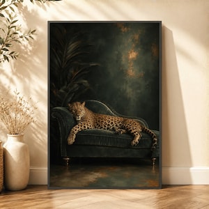 May include: A framed wall art print featuring a leopard resting on a dark teal velvet chaise lounge. The background is a moody, dark green textured wall with golden highlights. Large dark tropical leaves are visible behind the furniture.