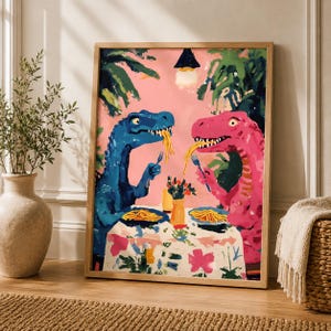 May include: A framed art print depicting two dinosaurs eating spaghetti. One is blue, the other pink, set against a pink backdrop with green leaves. The table has a floral tablecloth. The artwork is in a wooden frame.
