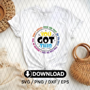 Op de afbeelding: Wit T-shirt met een kleurrijk cirkelontwerp met de tekst "You Got This" met de woorden "Don't Stress", "Rock the Test", "Do You Best", "You Can Do This" en "I Believe in You" rond de cirkel.
