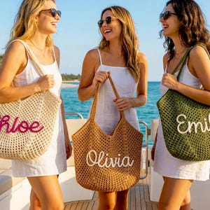 K&ouml;nnte beinhalten: Drei Frauen auf einem Boot mit personalisierten H&auml;keltaschen. Die Taschen sind beige, braun und olivgr&uuml;n, mit den Namen "Chloe", "Olivia" und "Emily". Die Frauen tragen Sonnenbrillen und wei&szlig;e Kleider und l&auml;cheln in die Kamera.