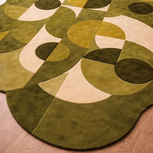 Könnte beinhalten: Ein grün-beiger Teppich mit geometrischem Muster. Der Teppich hat eine abgerundete Form und weist verschiedene Grüntöne, darunter Oliv- und Waldgrün, sowie Beige auf. Das Design umfasst Kreise, Halbkreise und andere geometrische Formen.