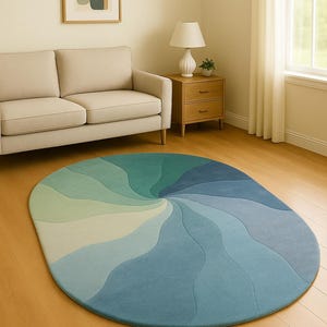 Könnte beinhalten: Ovaler Teppich mit einem Wirbelmuster in Blau- und Grüntönen. Der Teppich hat ein Farbverlaufsdesign, das von hellen zu dunklen Farbtönen übergeht. Er liegt auf einem Holzboden in einem Wohnzimmer. Ungefähre Abmessungen: 200 cm x 150 cm.