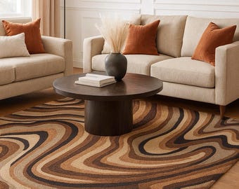 May include: A living room scene featuring a brown and beige patterned rug. The rug's design has a swirling pattern in shades of brown, tan, and black. The room also includes a beige sofa, armchairs, and a dark brown coffee table.