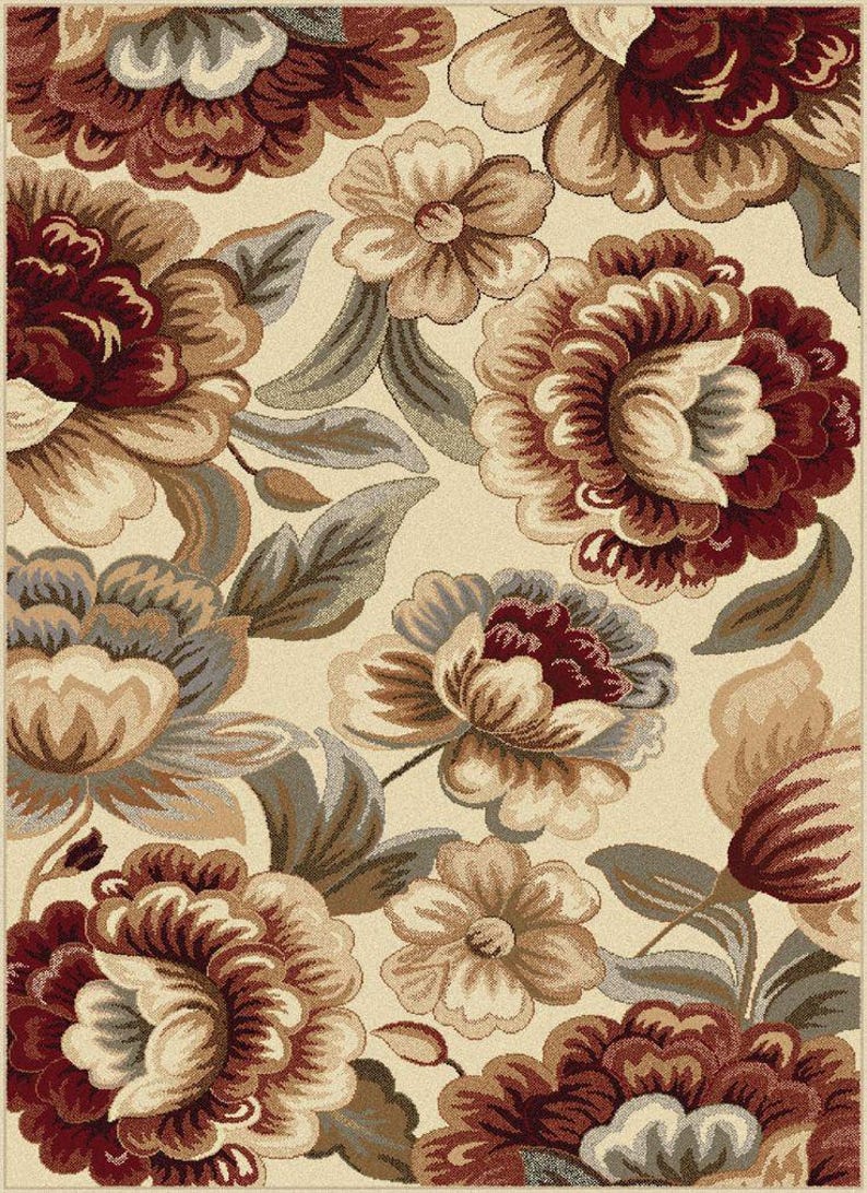 Puede incluir: Una alfombra floral con fondo crema y grandes flores detalladas en tonos burdeos, marr&oacute;n y beige. El dise&ntilde;o incluye hojas estilizadas en gris y marr&oacute;n, creando un aspecto cl&aacute;sico y elegante para cualquier espacio.