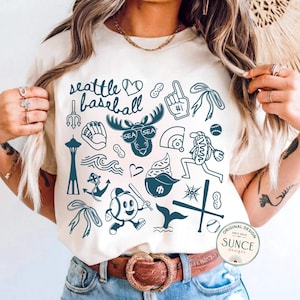 model wearing ivory comfort colors shirt that has doodle baseball designs and says seattle baseball