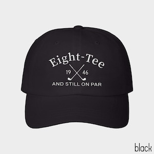 Puede incluir: Una gorra de b&eacute;isbol negra con texto bordado en blanco que dice Eight-Tee, con los n&uacute;meros 19 y 46 a cada lado de dos palos de golf cruzados, y el texto AND STILL ON PAR bordado en blanco debajo de los palos de golf.