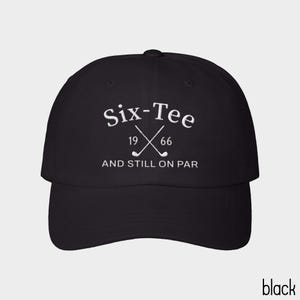 May include: A black baseball cap featuring white embroidered text that reads Six-Tee 19 66 AND STILL ON PAR, with a graphic of two crossed golf clubs positioned between the numbers 19 and 66 on the front panel of the hat.