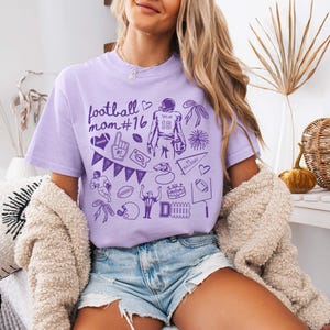 May include: A light purple short-sleeve t-shirt featuring a dark purple graphic print with the text football mom #16, a football player with the number 16, a foam finger, a pennant, a whistle, a stadium, a goal post, and various football icons.