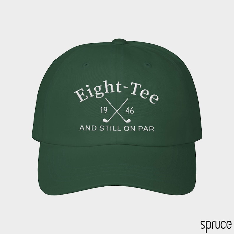 Puede incluir: Una gorra de b&eacute;isbol de color verde oscuro con texto bordado en blanco que dice Eight-Tee, 19 46 y AND STILL ON PAR, junto con un gr&aacute;fico de dos palos de golf cruzados situados entre los n&uacute;meros 19 y 46 en el panel frontal.