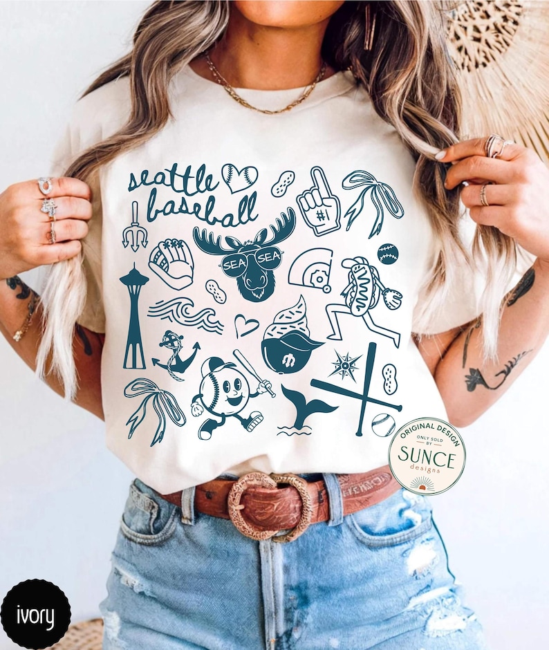 model wearing ivory comfort colors shirt that has doodle baseball designs and says seattle baseball
