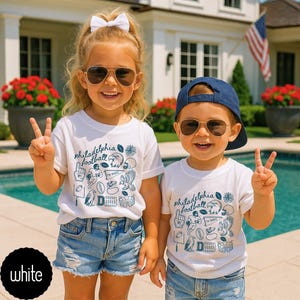 May include: Two children wearing white t-shirts with a blue graphic that says "Philadelphia football". They are also wearing sunglasses and denim shorts. The children are smiling and holding up peace signs.