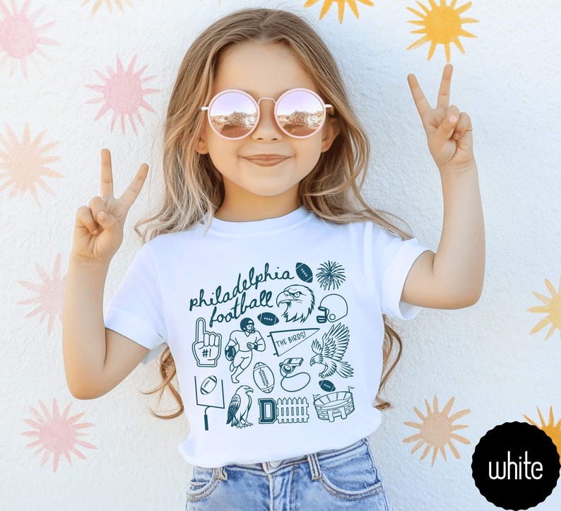 toddler model wearing white rabbit skins tee shirt with a football doodle design and says philadelphia football