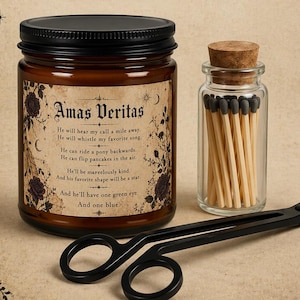 May include: A candle set with a jar candle, matches in a glass bottle, and a wick trimmer. The candle jar has a black lid and a label with text and floral designs. The set is labeled "THE FULL RITUAL candle set".