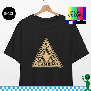 Puede incluir: Camiseta negra con un símbolo Lambda dorado dentro de un triángulo. La palabra "Lambda" está en cada lado del triángulo, con estrellas en cada esquina. Tallas: S-4XL. La imagen también incluye un gráfico de "Más colores".