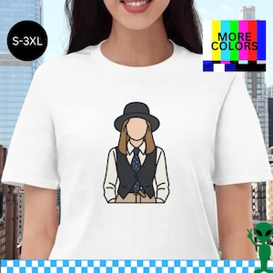Puede incluir: Camiseta blanca con una ilustración de dibujos animados de una persona con sombrero, chaleco y corbata. La camiseta tiene el texto "MORE COLORS" y las tallas "S-3XL". El diseño es un gráfico estilizado y minimalista.