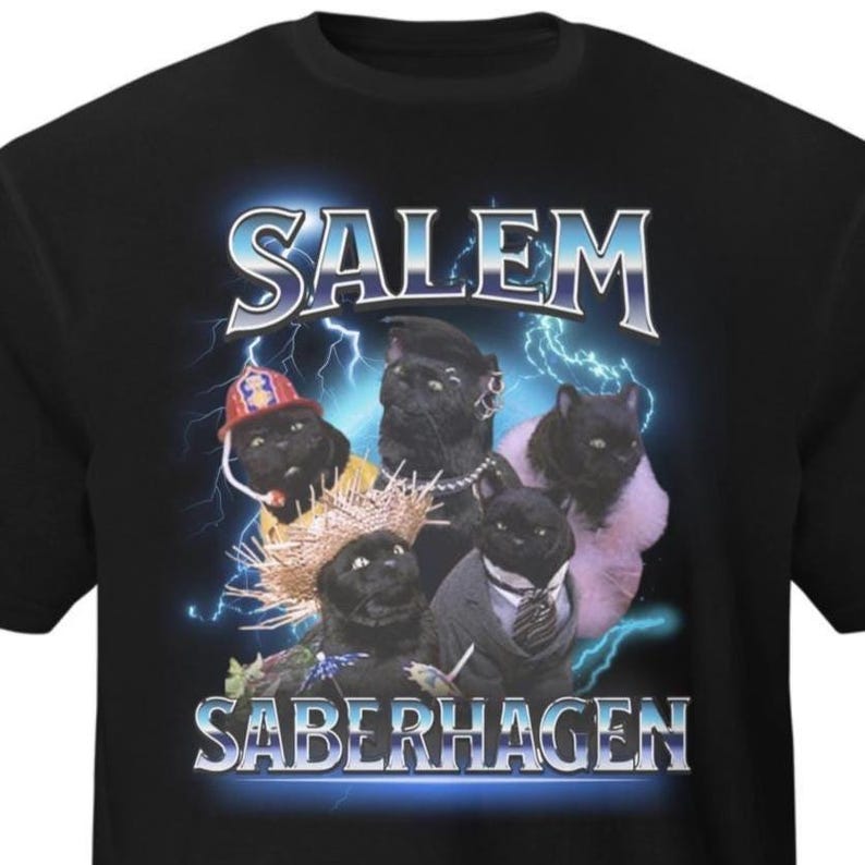 May include: Black t-shirt with a graphic of five black cats in costumes, including a firefighter's hat and a suit. The words "SALEM" and "SABERHAGEN" are in a silver, stylized font with a lightning bolt effect.