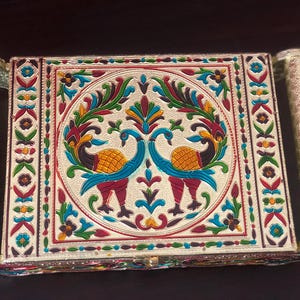May include: A silver tray featuring a colourful design of two peacocks with intricate details. The tray has a raised border and two handles on the sides.