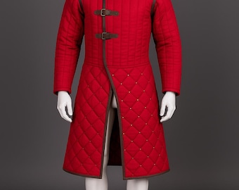 May include: A red quilted coat with brown trim and three buckle closures. The coat features a high collar and a diamond pattern. The mannequin is wearing a long coat with a split front, perfect for historical reenactments or costume events.
