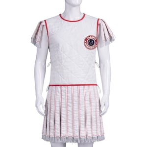 Puede incluir: Conjunto de armadura romana acolchada blanca con ribetes y detalles en rojo. El conjunto incluye una parte superior sin mangas y una falda plisada, ambas con costuras verticales rojas. La armadura tiene un emblema redondo que dice "TAGOWN HANDICRAFTS".