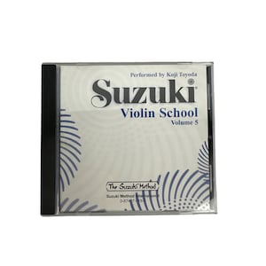 Pode incluir: Uma caixa de CD transparente contendo um CD de "Suzuki Violin School Volume 5". A capa apresenta a palavra "Suzuki" em uma fonte grande e estilizada, com "Violin School" abaixo. O texto "Performed by Koji Toyoda" está no topo.