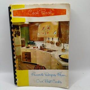 Könnte beinhalten: Ein Vintage-Kochbuch mit gelbem und orangefarbenem Einband. Der Titel "Cook Book" ist in Orange gehalten, und der Untertitel "Favorite Recipes From Our Best Cooks" ist blau. Das Cover zeigt eine Retro-Küchenszene.