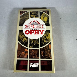 Pode incluir: Uma fita VHS para "Country's Family Reunion at the Opry, Volume Four". A capa apresenta uma colagem de artistas em tons sépia, com o título em um emblema circular. A fita está em uma caixa retangular com um esquema de cores bege e marrom.